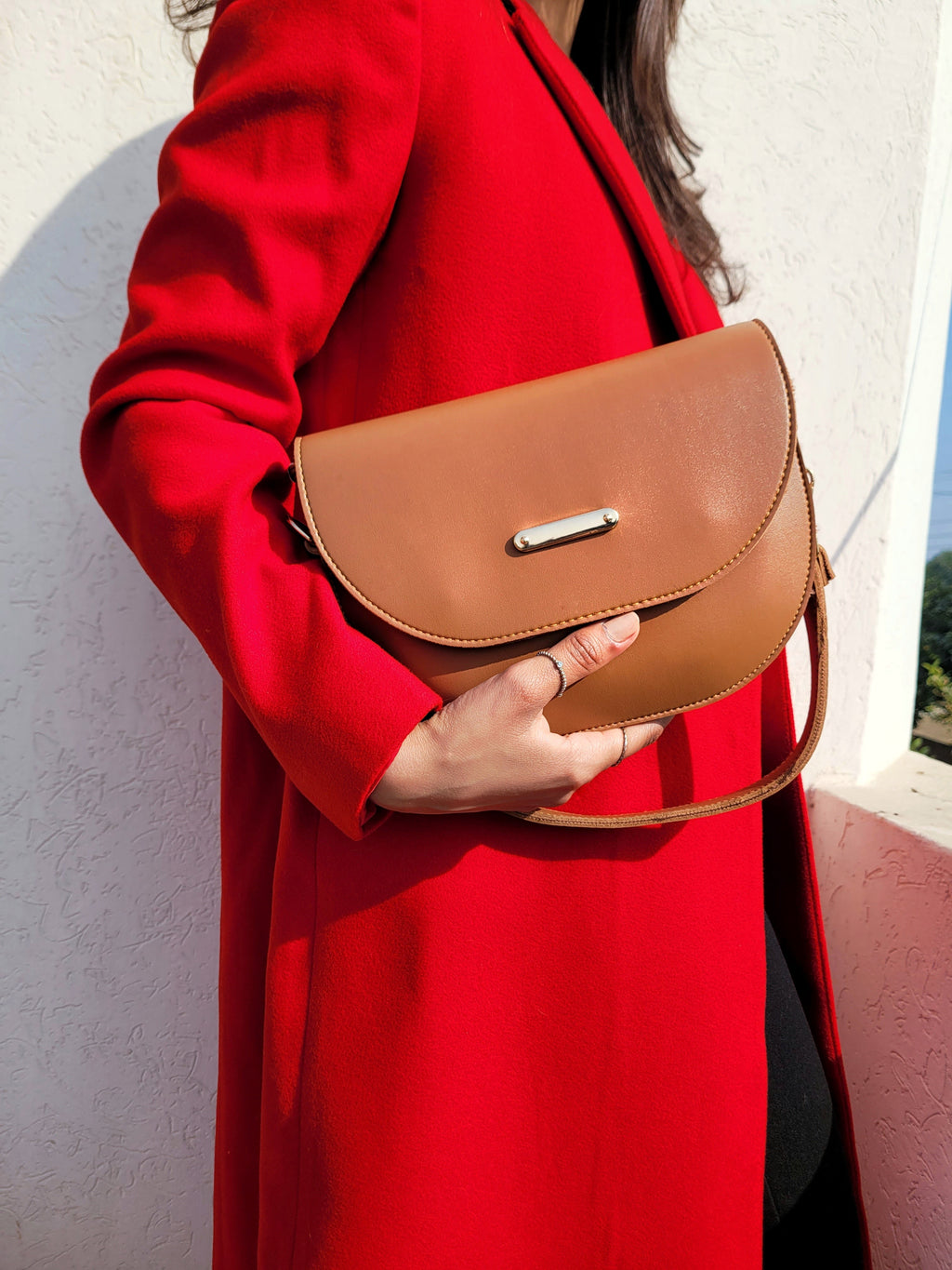Woman holding chic brown handbag wearing red coat