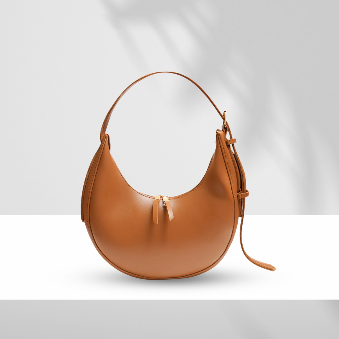 Brown U-shaped synthetic leather bag with single zipper and adjustable shoulder strap on white background