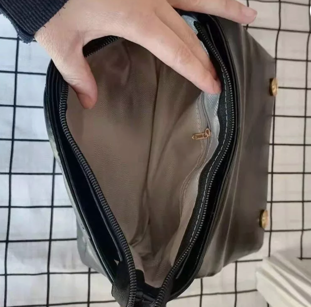 Open view of a stylish brown faux leather handbag showing spacious beige interior with zipper pocket and chain detail