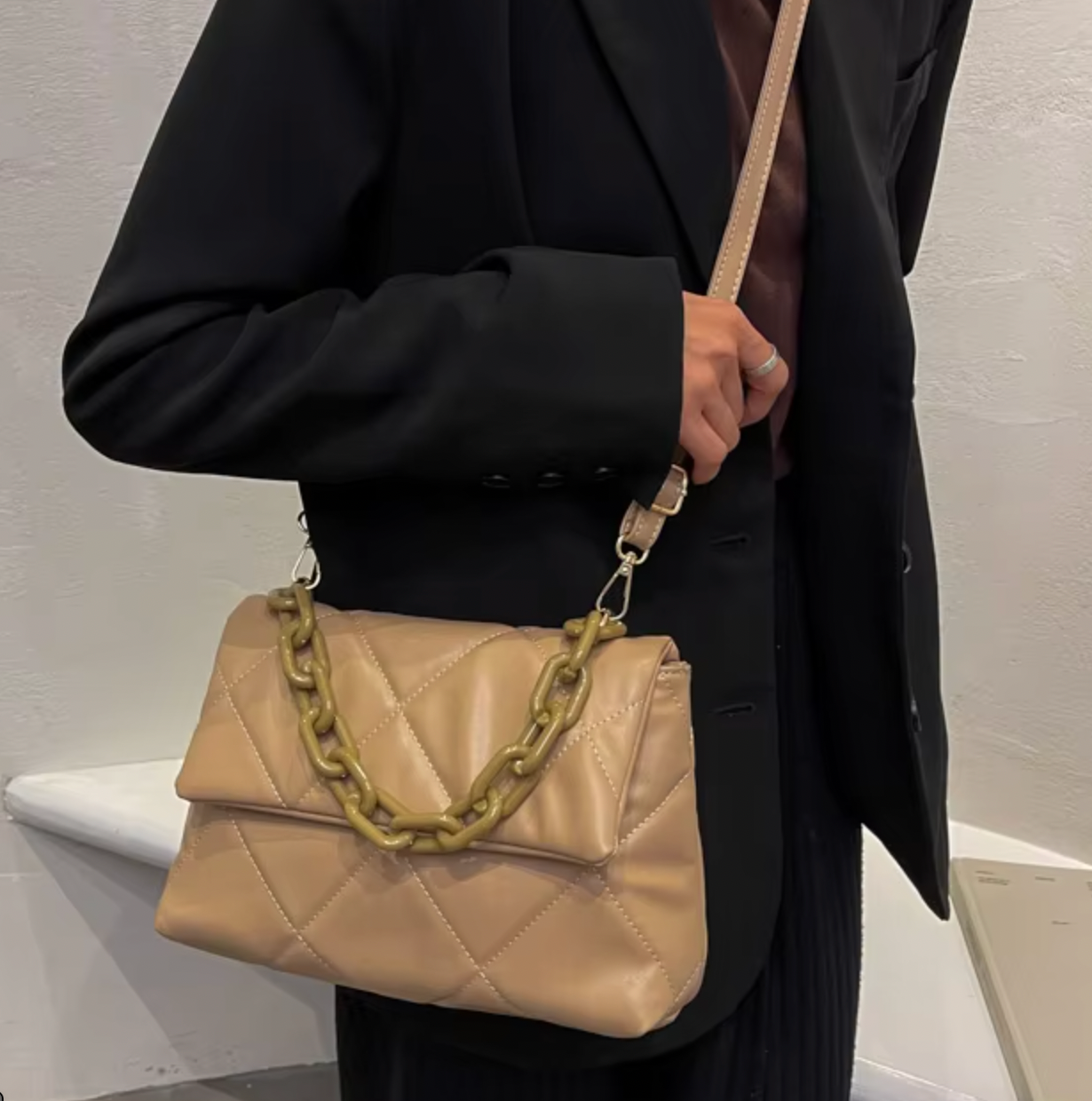 Woman wearing black blazer holding a fluffy quilted brown handbag with chain detail on shoulder
