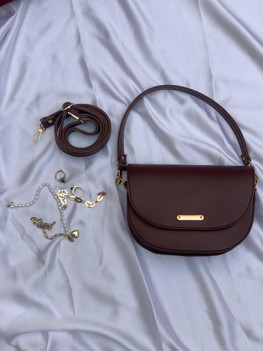 Dark brown dual strap bag with gold hardware, adjustable crossbody strap, and top handle on white fabric background.