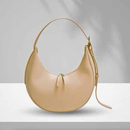 Beige U-shaped synthetic leather bag with single zipper and adjustable shoulder strap displayed on white surface